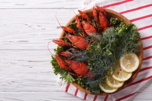 crayfish with fresh herbs and lemon on wooden plate. Horizontal top view