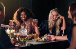 Venner skåler rundt et dekket bord med mat og drikke