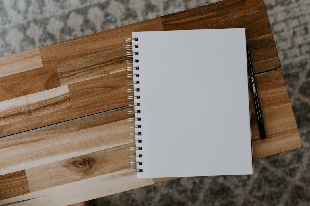 Åpen, blank notatbok og blyant på et trebord